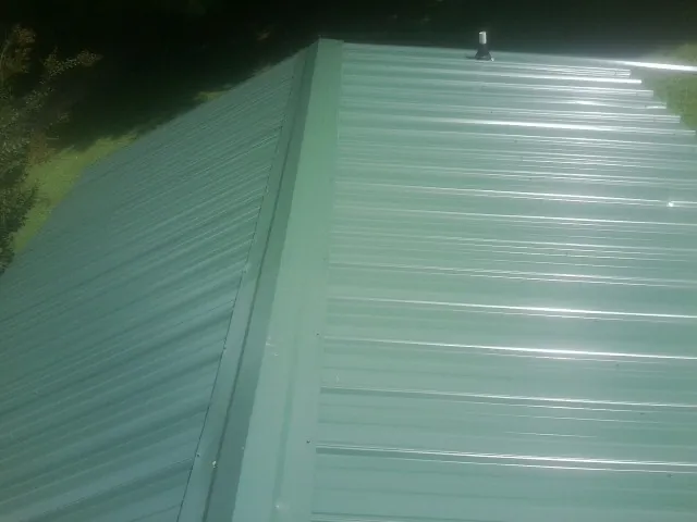 New green metal panels meeting at the ridge of a roof — Flat Roof Repair work by our crew in Tuppers Plains