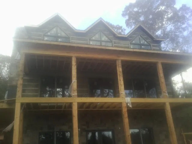 Dormers and porch framing on a large log home under construction — Roof Coating work by our crew in Tuppers Plains