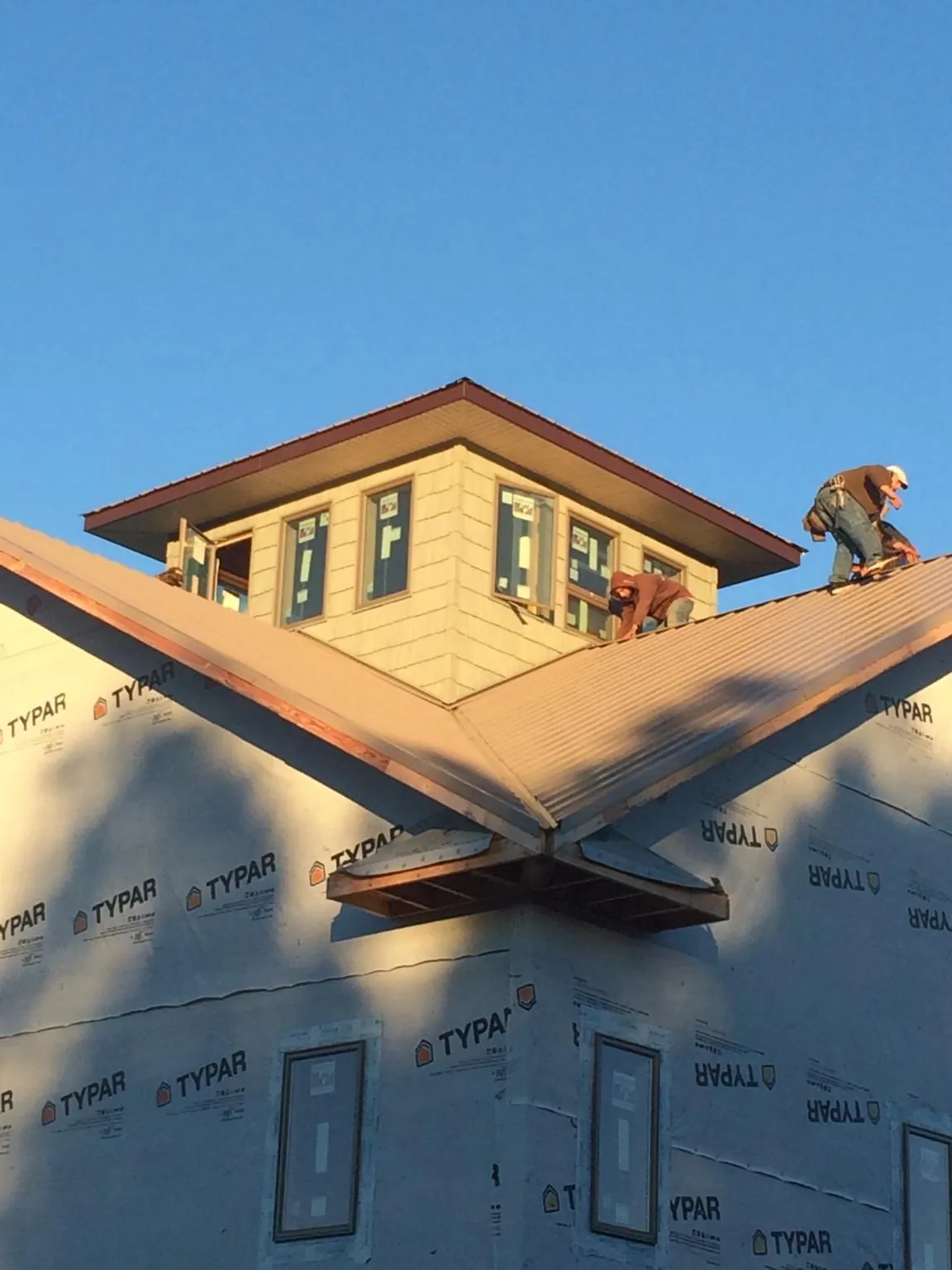 Roofers working around a rooftop cupola on a new metal roof at sunset — Roof Waterproofing in Tuppers Plains by Roofing Brothers